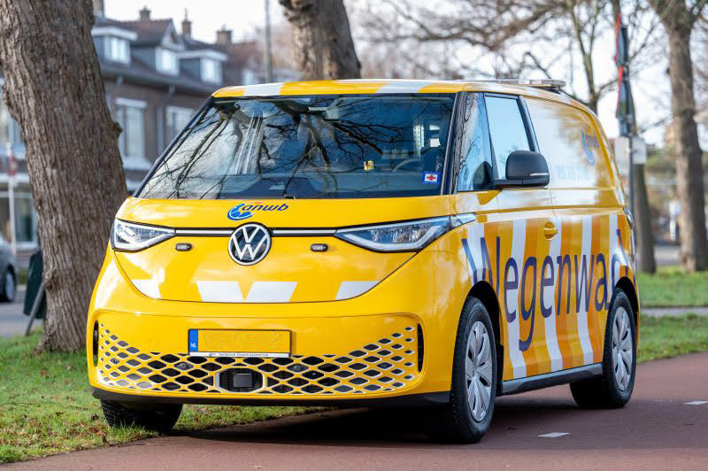 Een gele wegenwachtbus van de ANWB staat geparkeerd langs de weg.