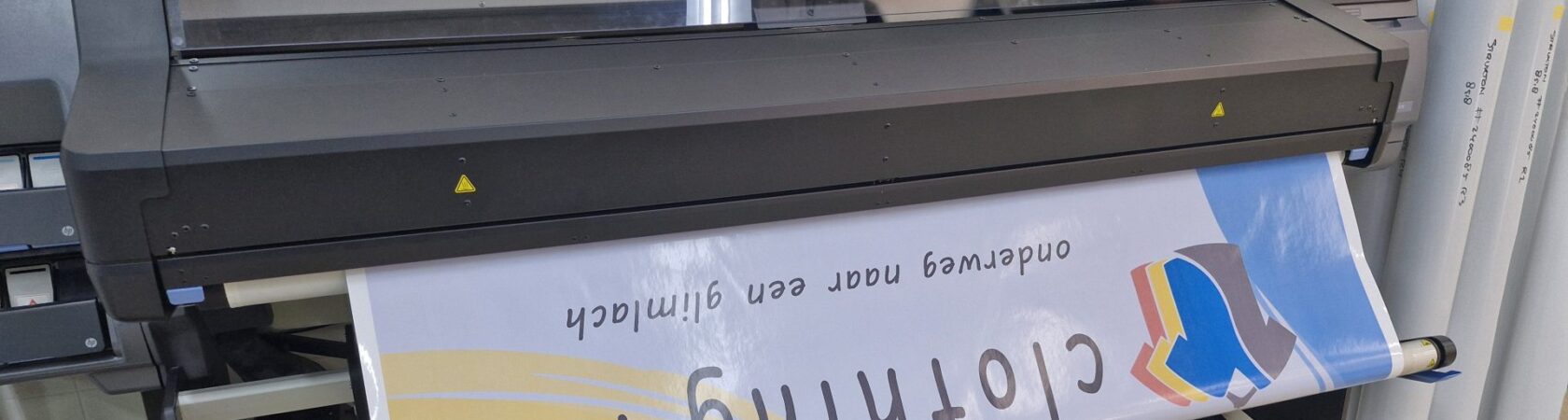 Een groot formaat printer drukt een banner af met het logo van 