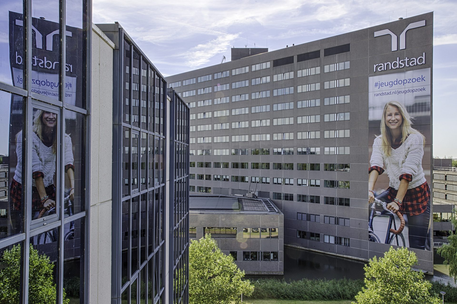 Gebouw van Randstad met een groot advertentiebord waarop een jonge vrouw op een fiets staat afgebeeld.