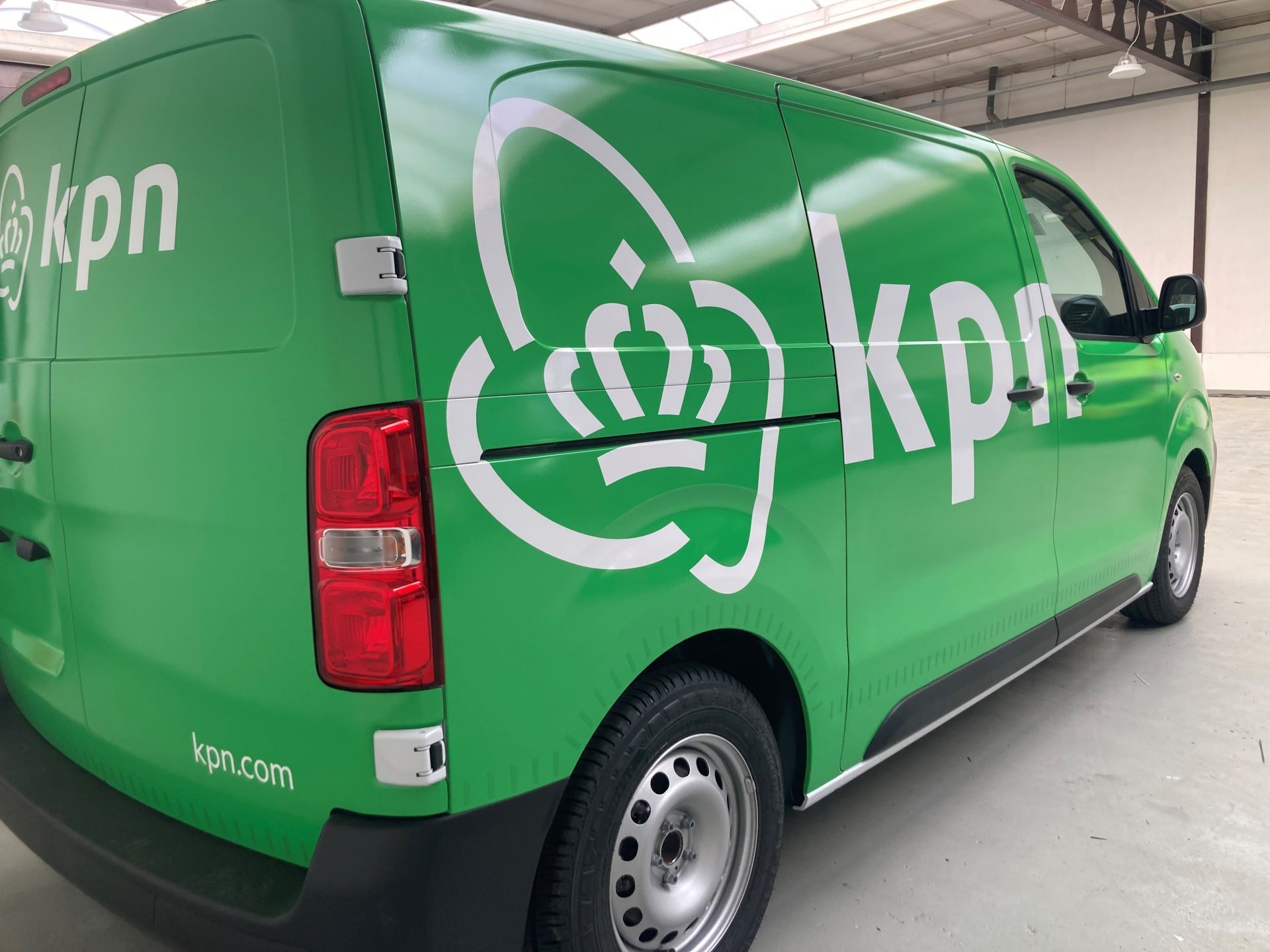 Een groene bestelwagen met het logo en de tekst van KPN erop.