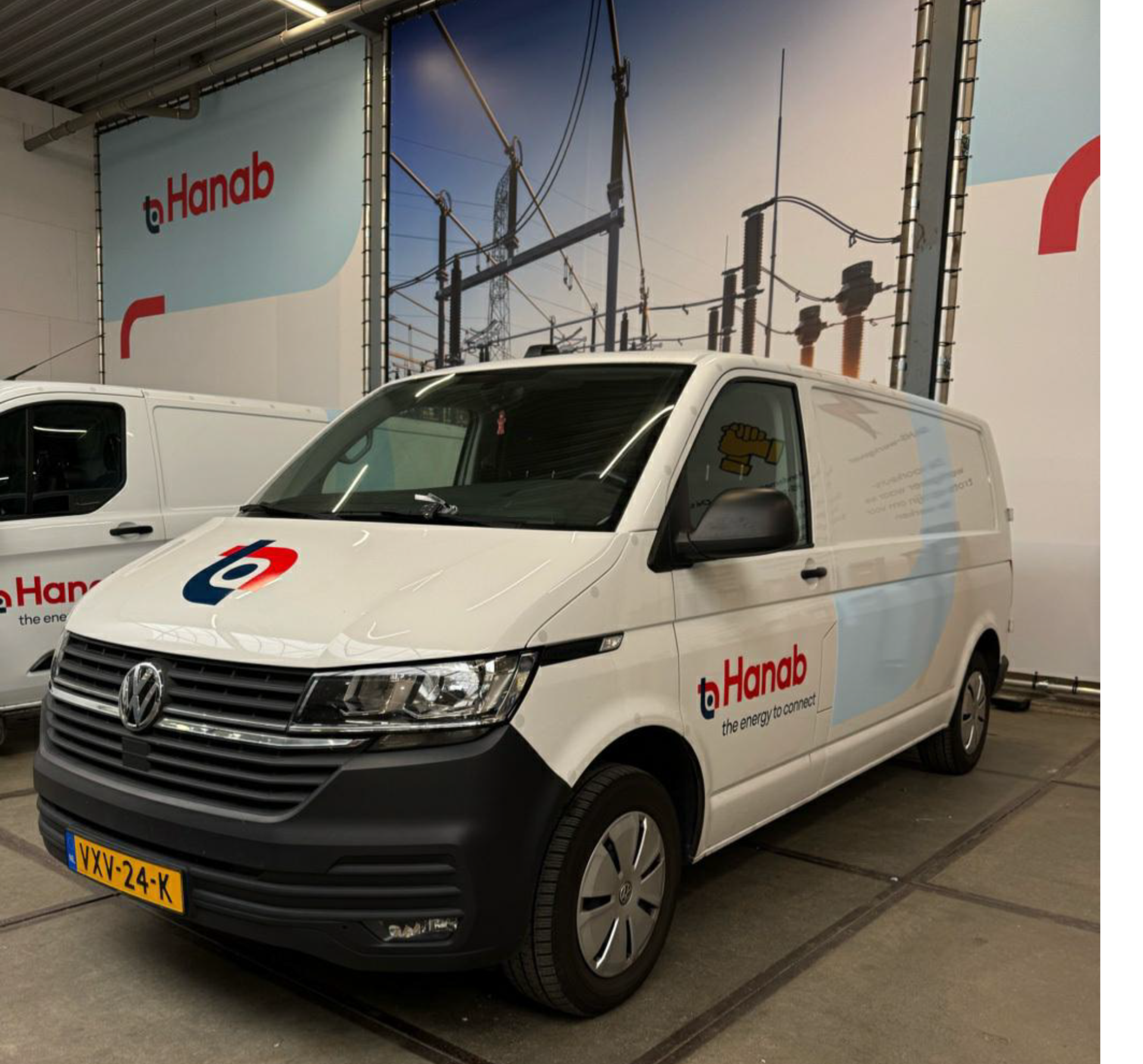 Een witte bedrijfsbus met het logo van Hanab staat geparkeerd in een garage.