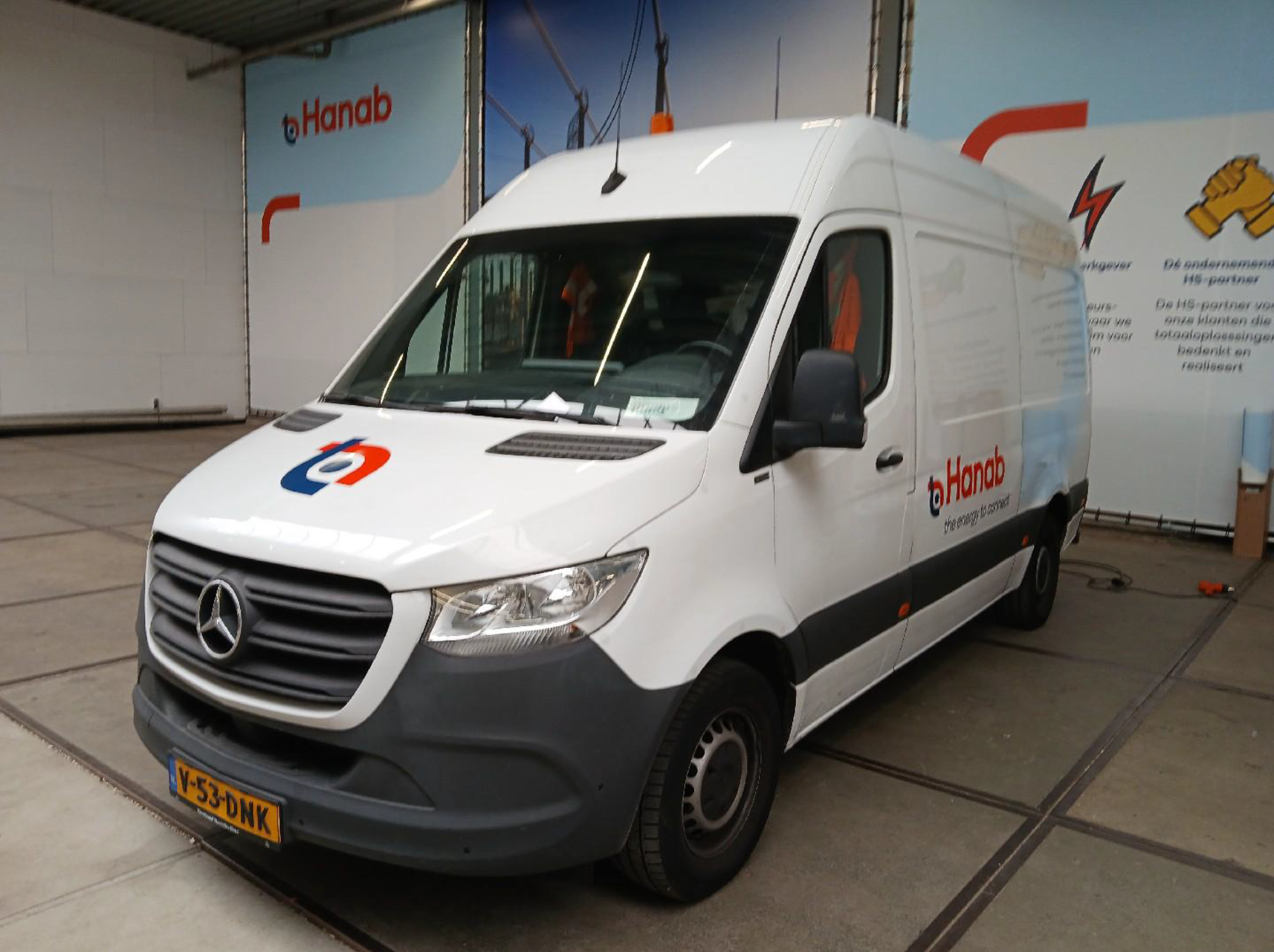 Witte bestelwagen met Hanab-logo geparkeerd in een werkplaats.