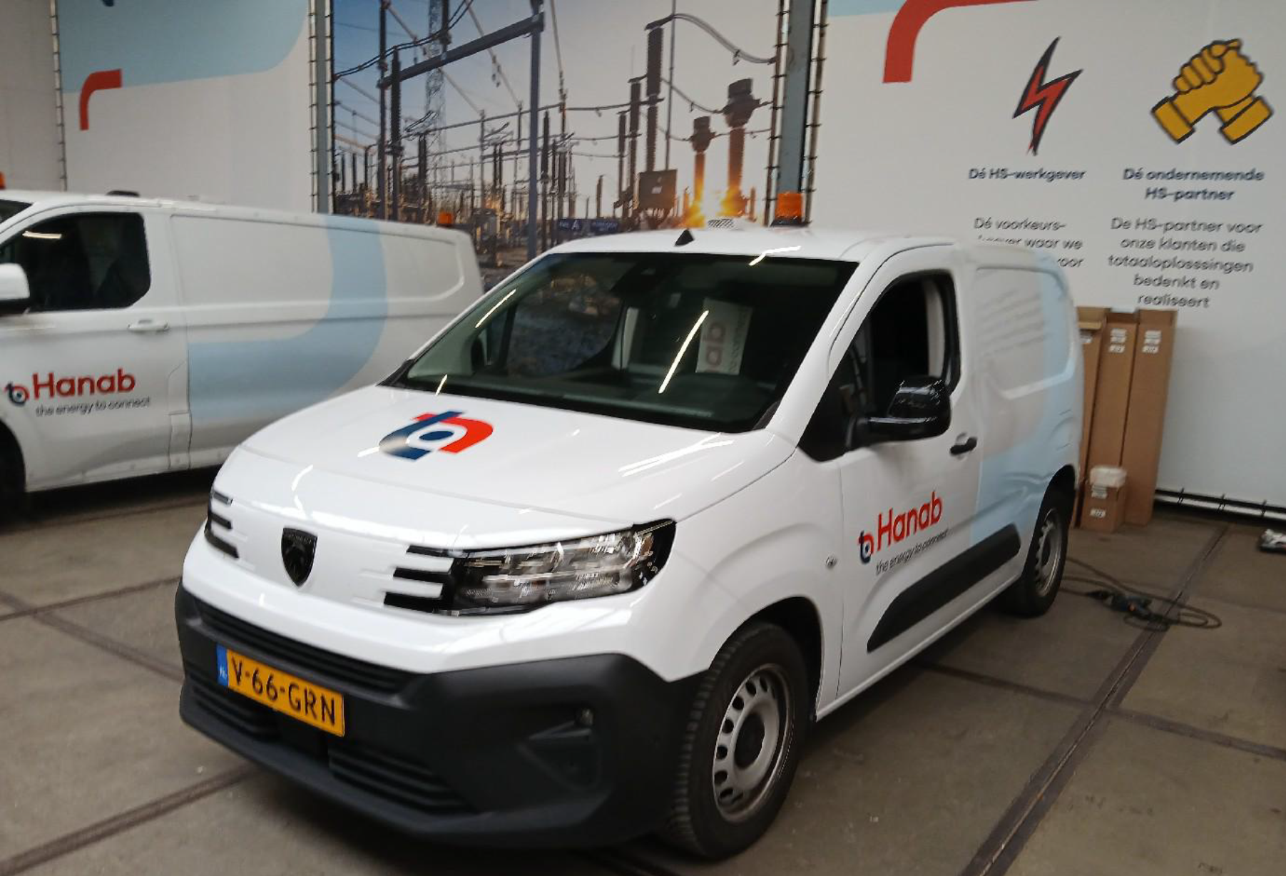 Een witte bestelwagen met het logo van Hanab staat in een industriële ruimte geparkeerd.