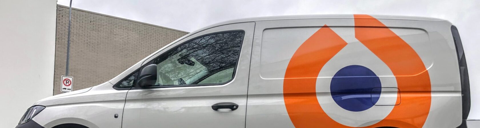 Een bestelwagen met het logo van Koninklijke Kuijpers staat geparkeerd op een stoep.