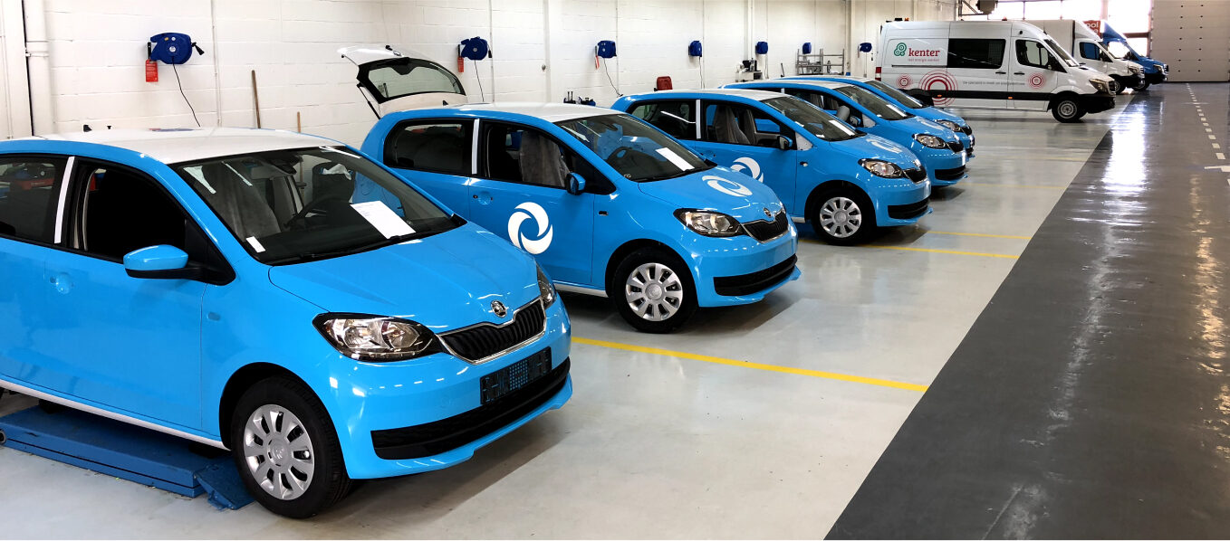 Rij van blauwe auto's met bedrijfslogo geparkeerd in een garage.