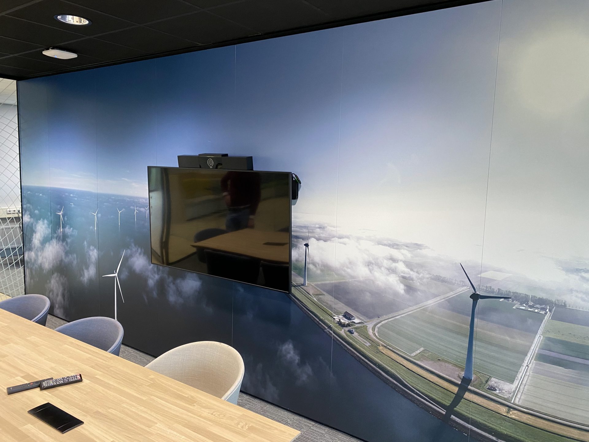 Vergaderruimte met een muurdecoratie van windmolens en een grote monitor.