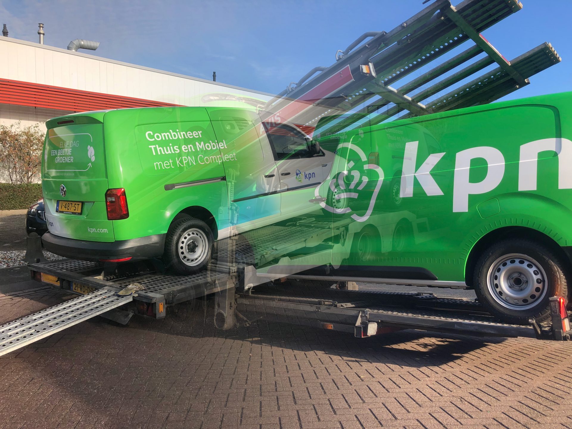 Een groene KPN bedrijfswagen wordt geladen op een trailer voor transport.