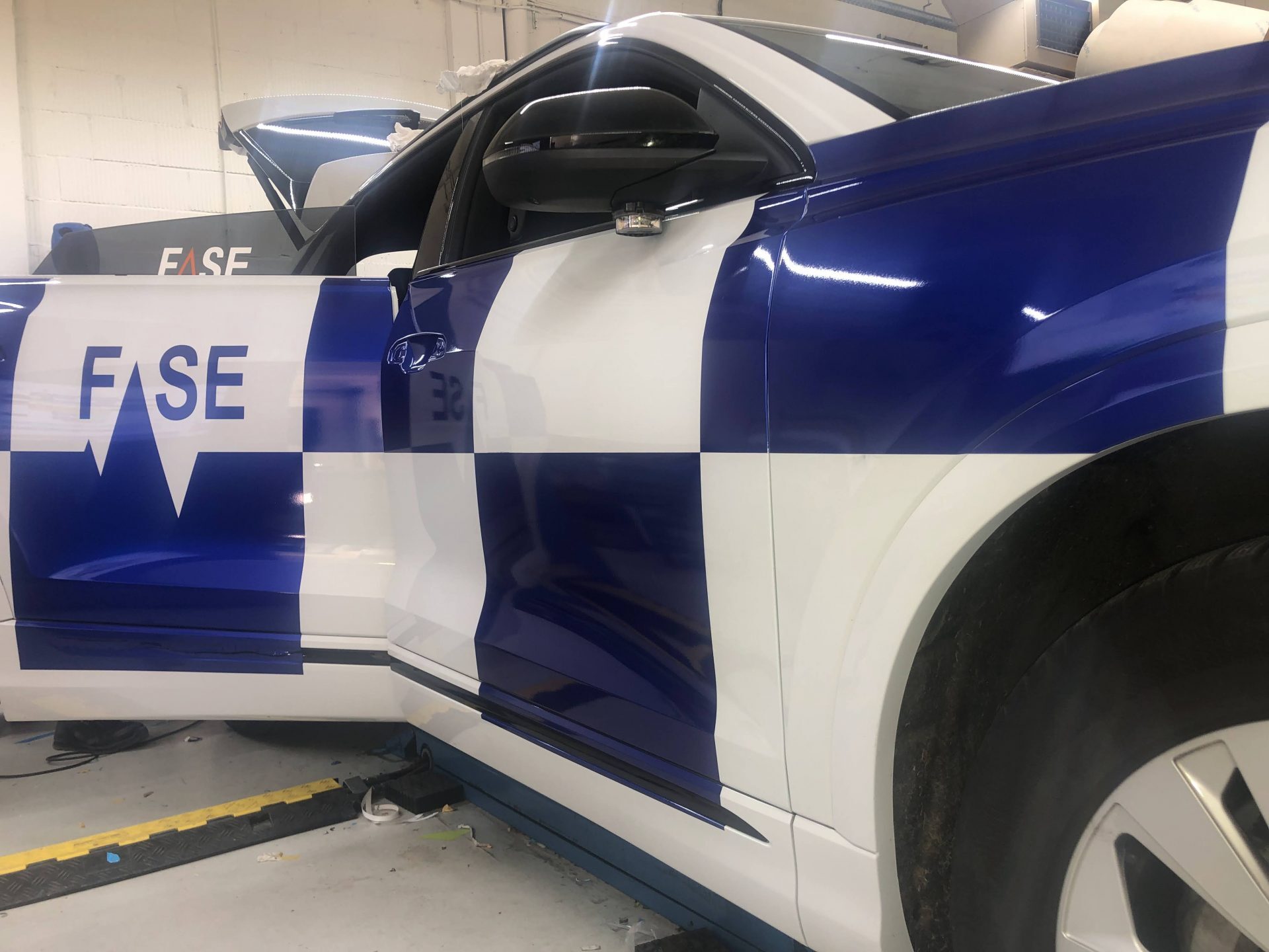 Een auto met een blauw-wit geruit patroon en de tekst 