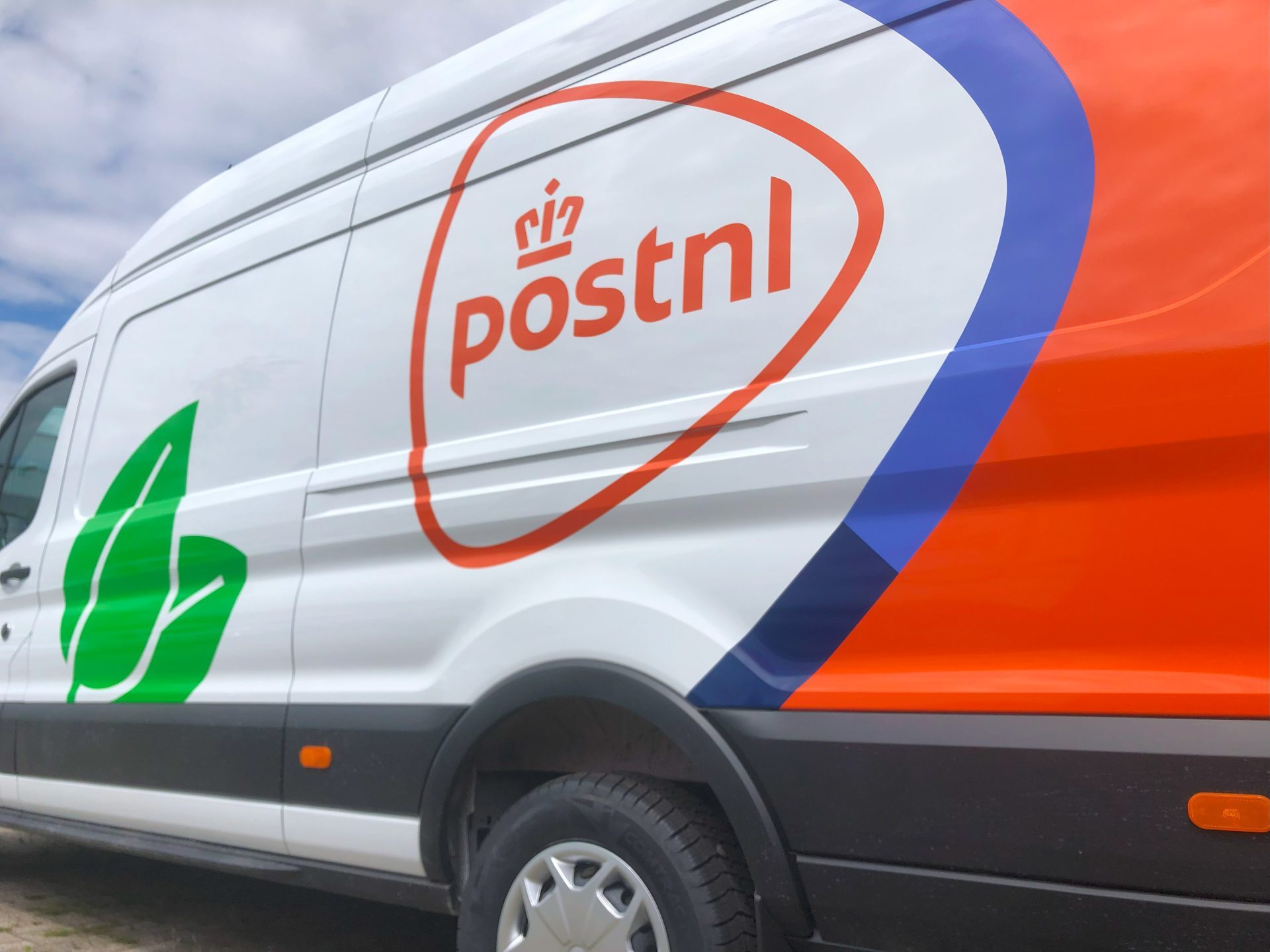 Bestelwagen met het logo van PostNL en een groen bladsymbool op de zijkant.