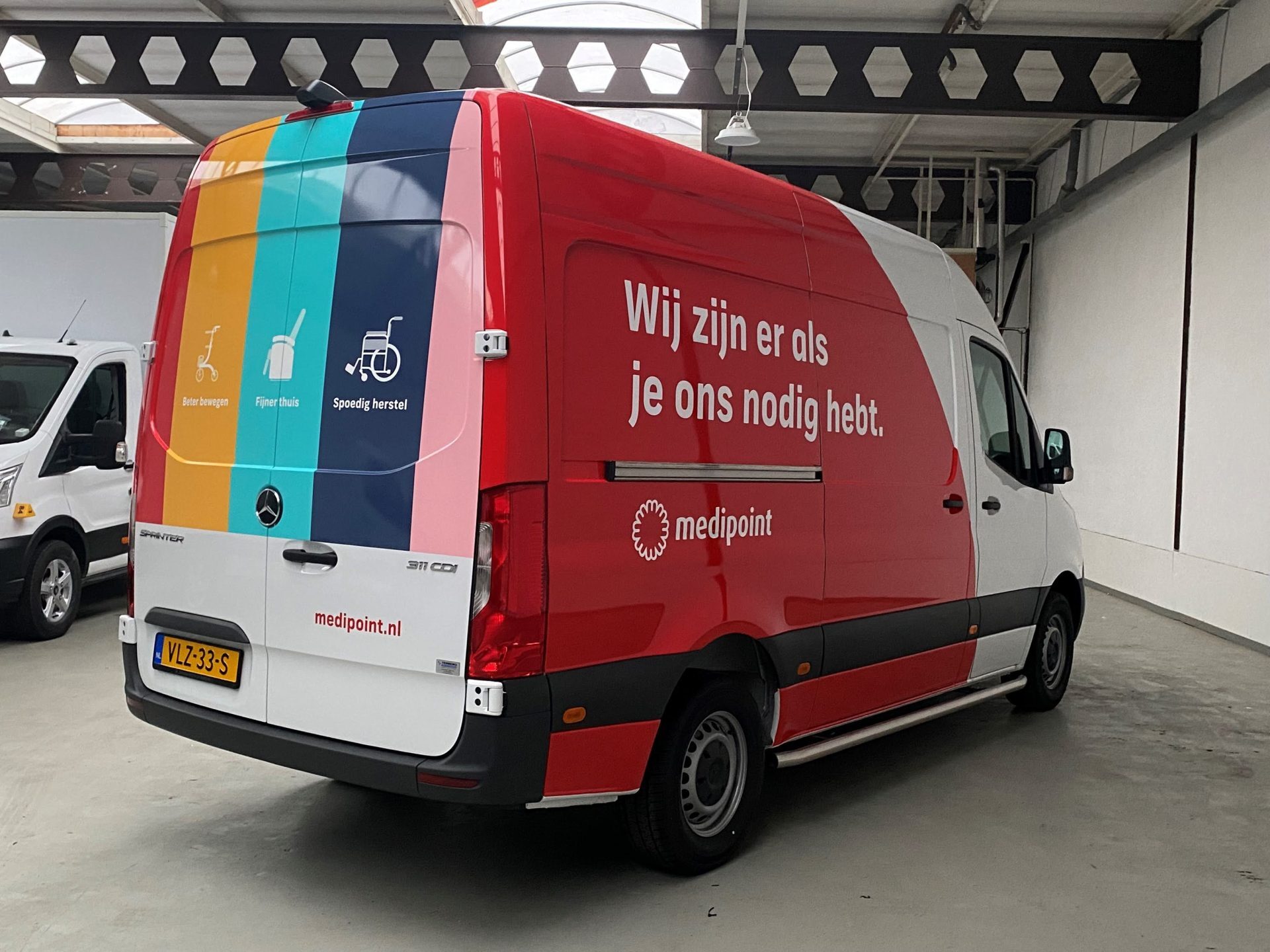 Rode en witte bestelbus van Medipoint met kleurrijke achterkant en tekst 