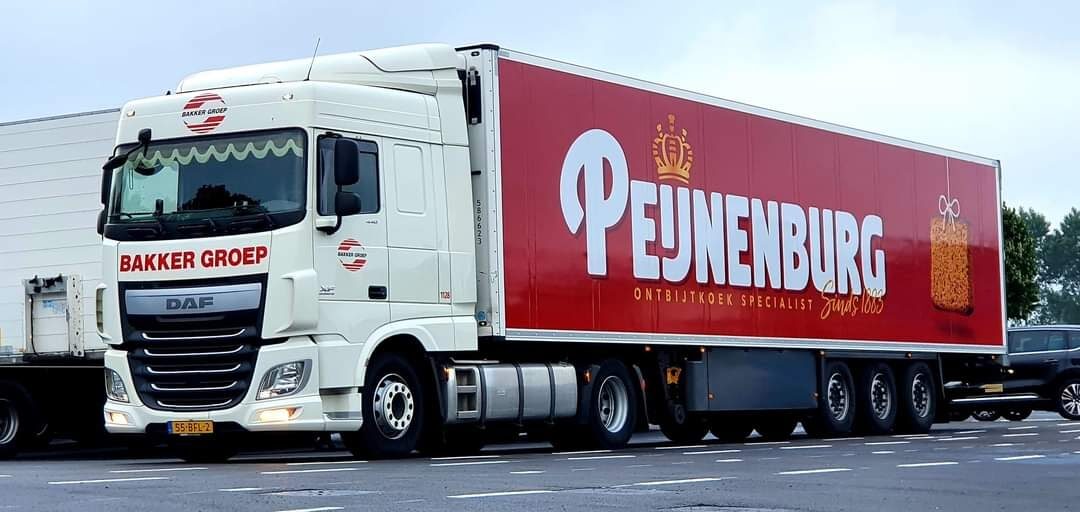 Vrachtwagen van Bakker Groep met een oplegger waarop het logo van Peijnenburg en een afbeelding van ontbijtkoek staan.