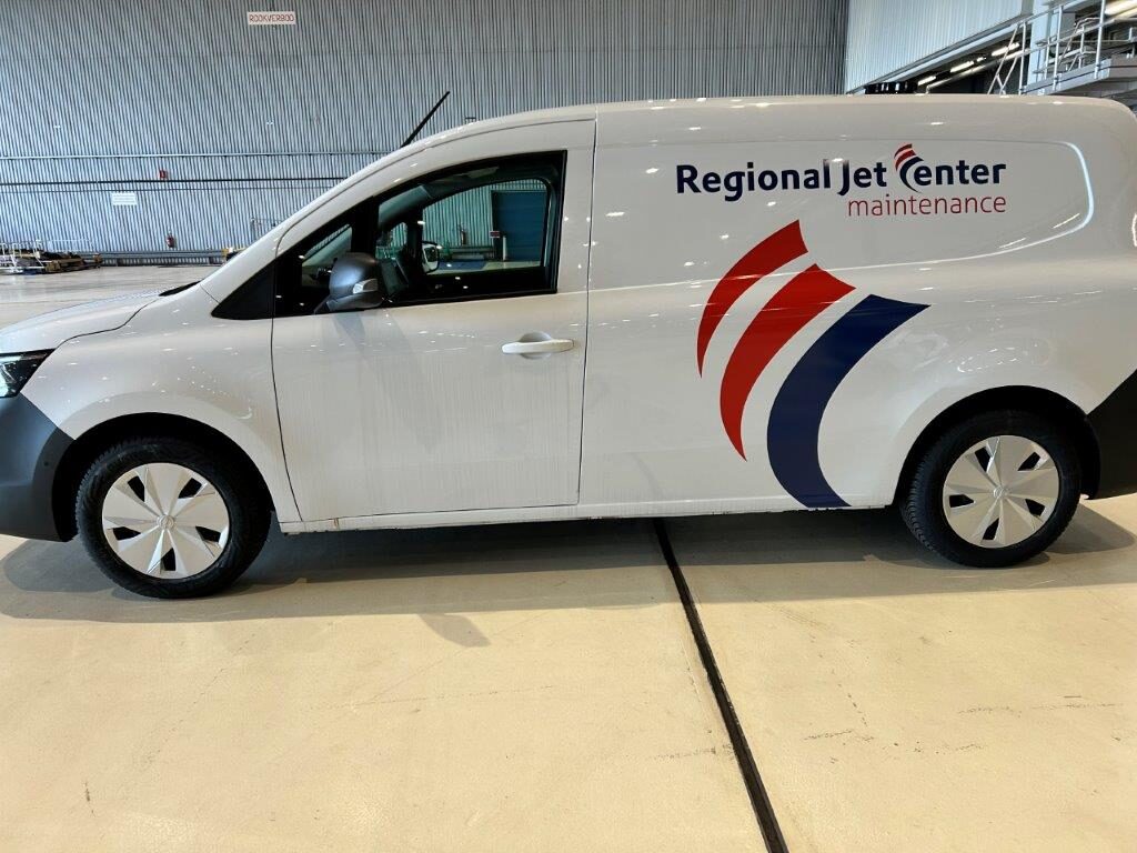 Een witte bestelwagen met het logo van Regional Jet Center Maintenance geparkeerd in een hangar.