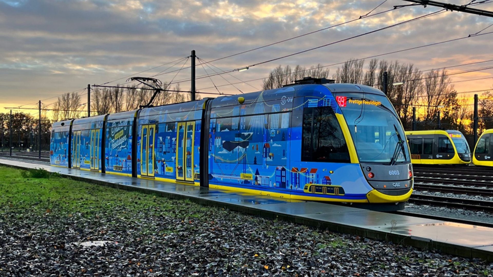 Een kleurrijk beschilderde tram staat op de rails bij zonsondergang.
