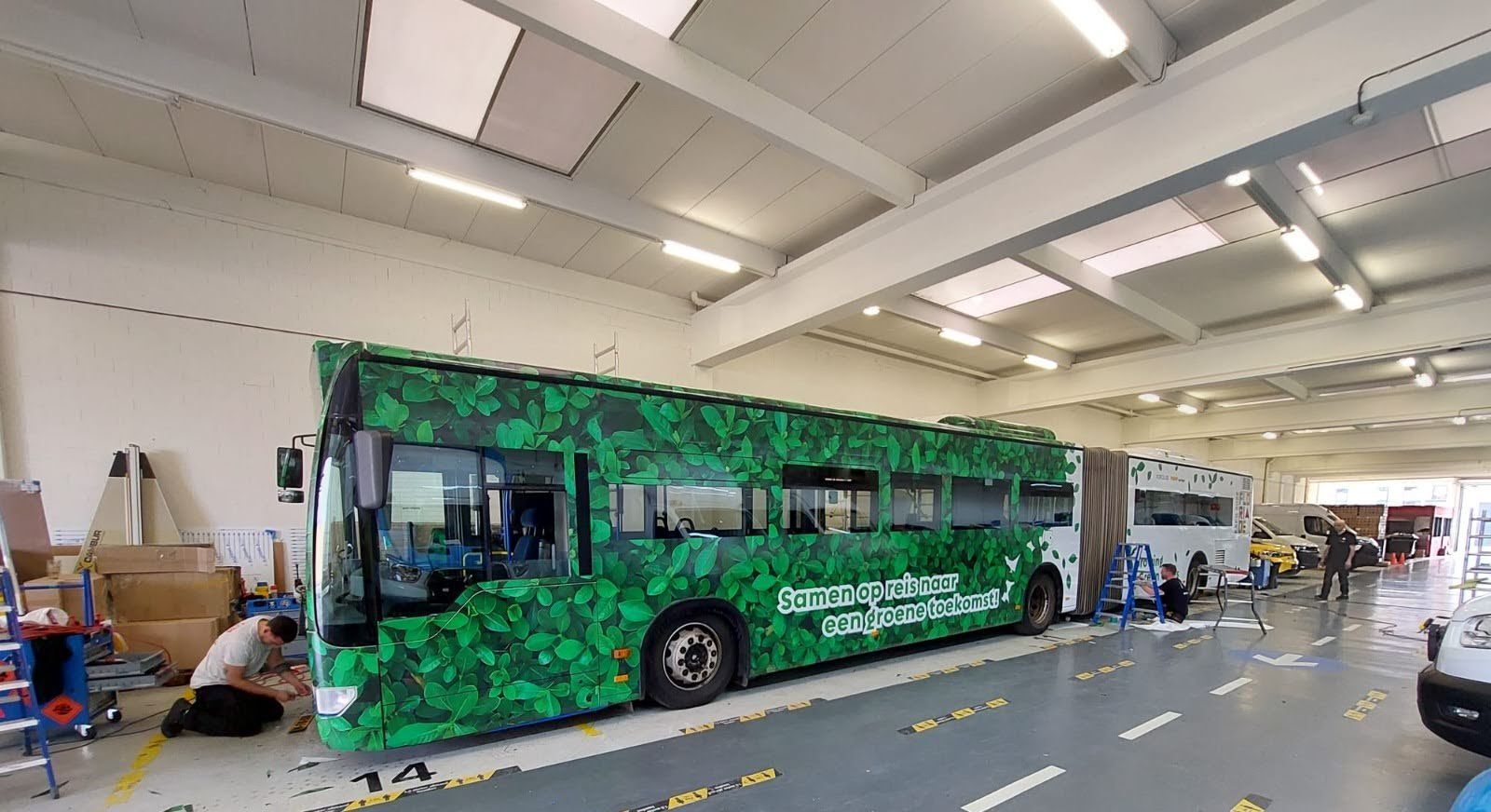 Een bus met groene bladpatronen en de tekst 