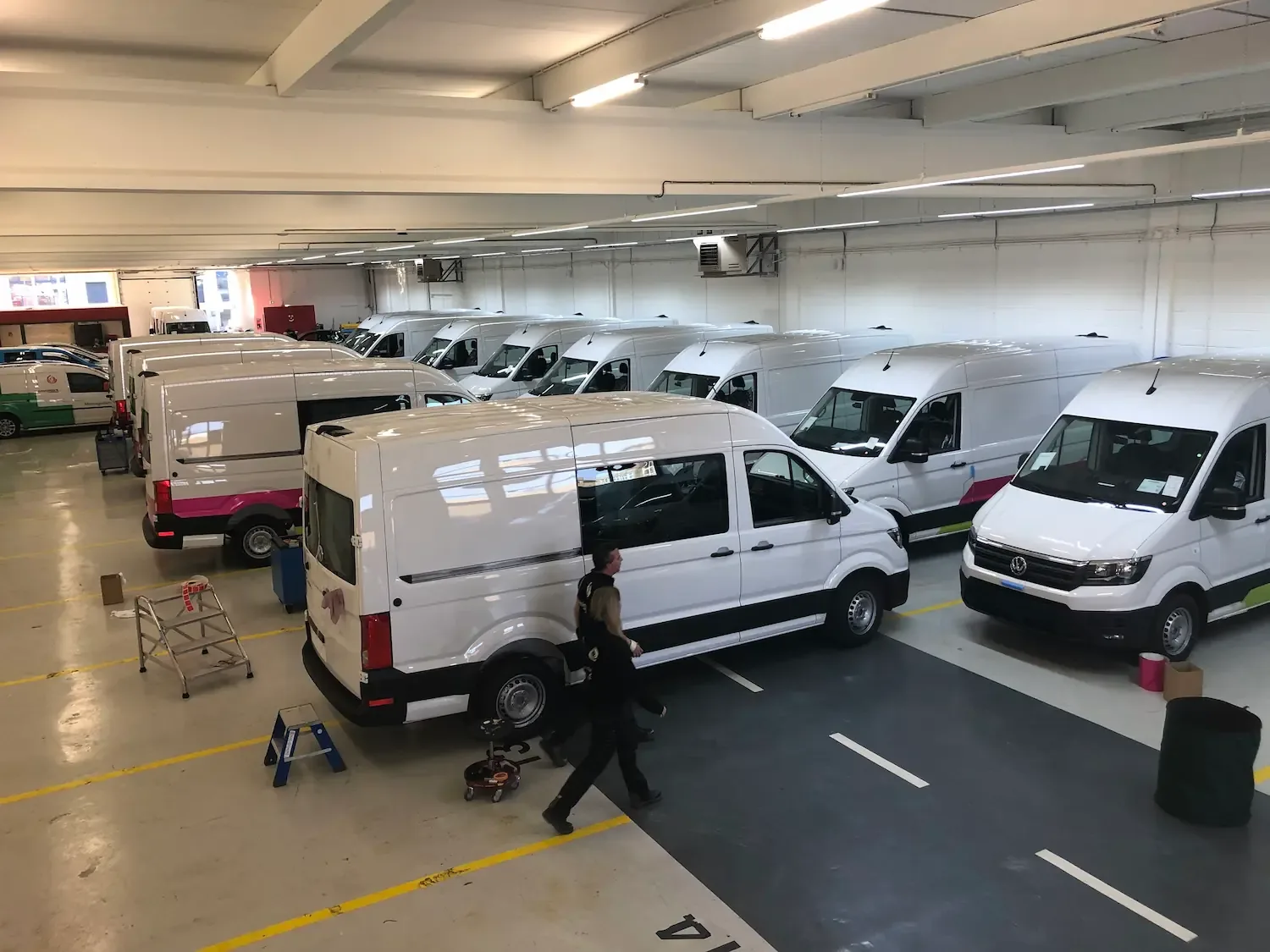 Een garage met meerdere geparkeerde witte bestelwagens.