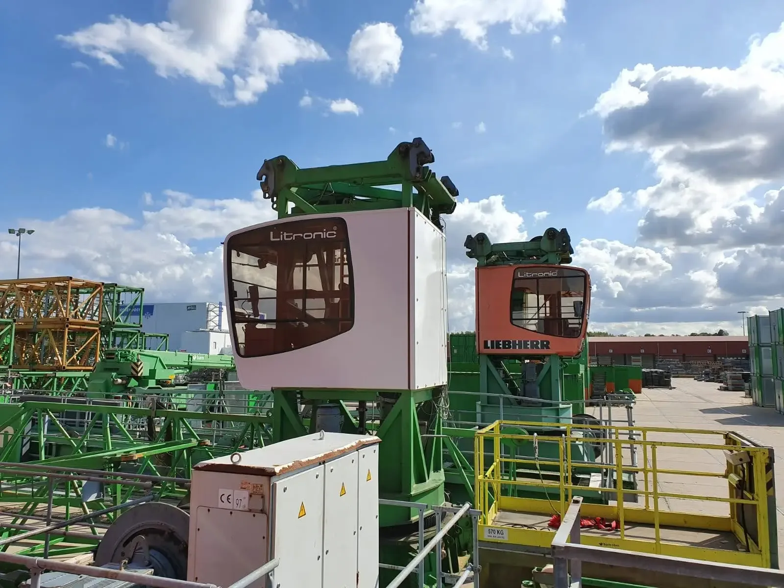 Twee bouwkraancabines van het merk Liebherr op een bouwplaats onder een bewolkte lucht.