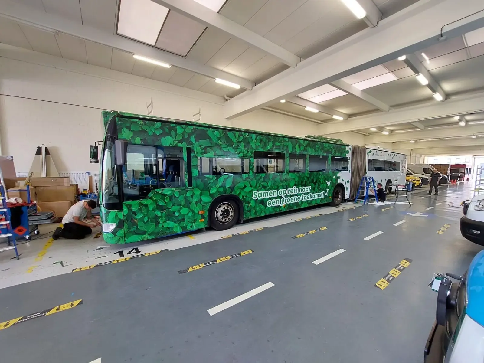 Een groene bus met bladermotief en de tekst 