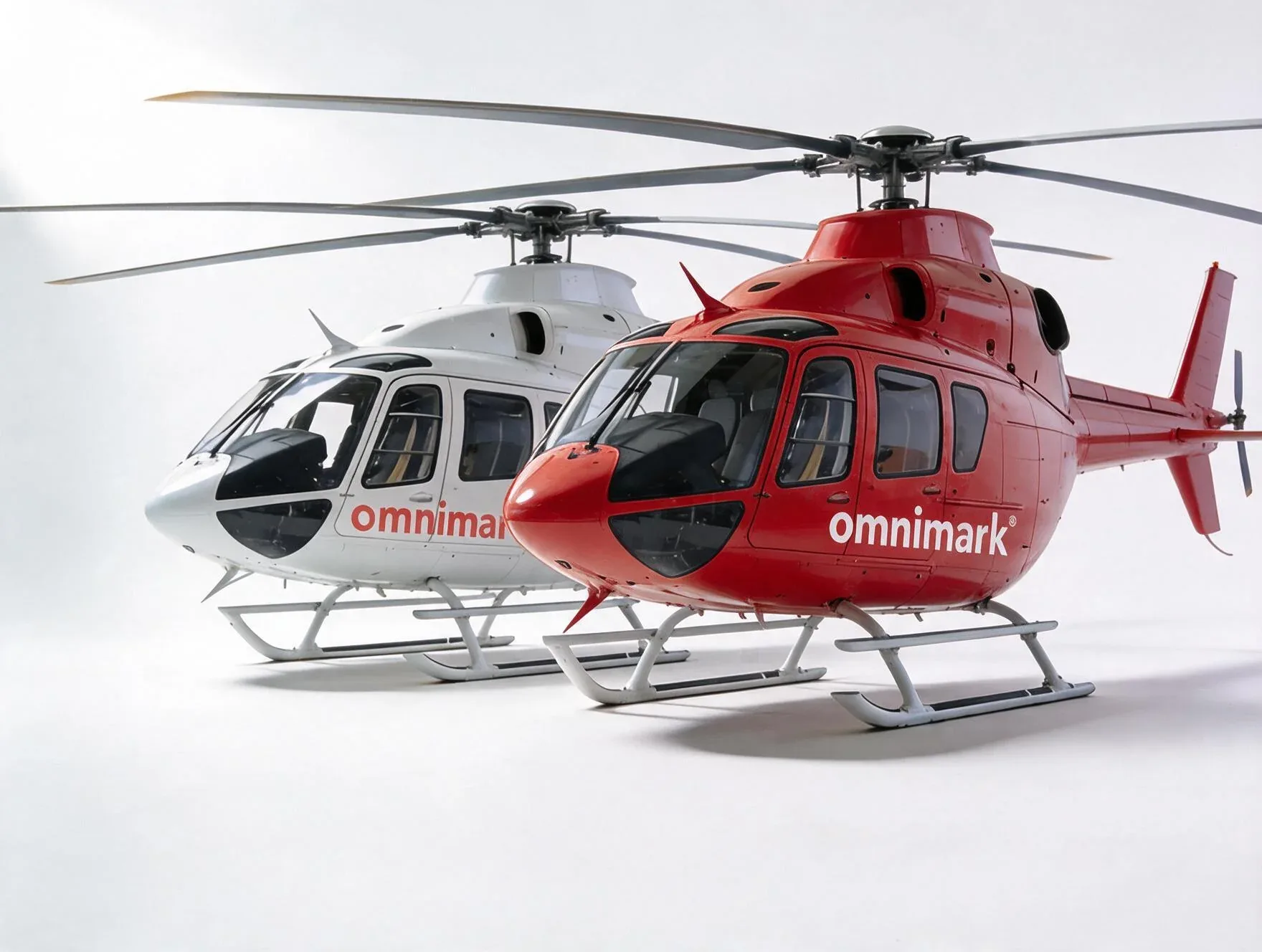 Twee heli's van Omnimark, een rode en een witte, staan naast elkaar.