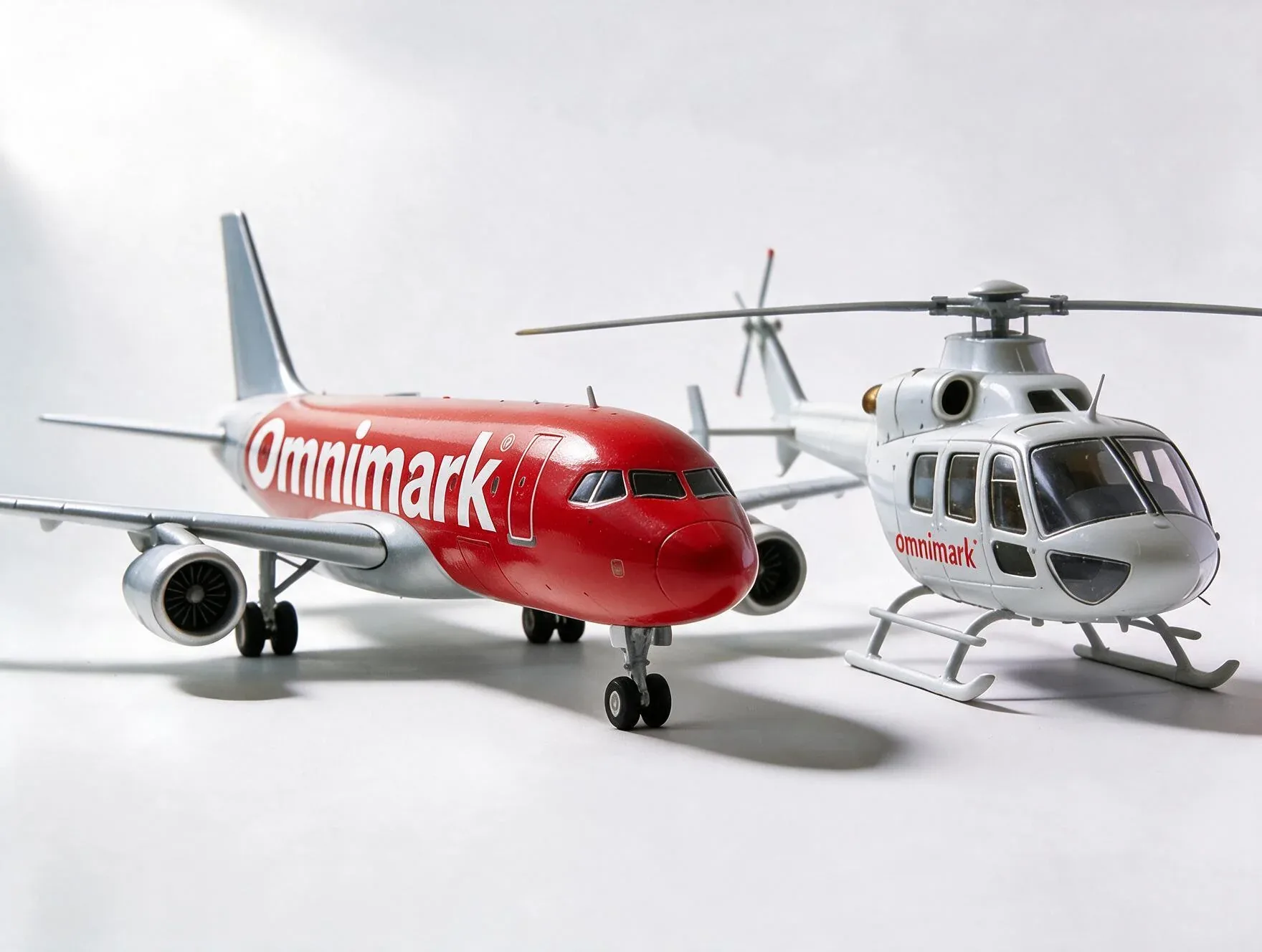 Een schaalmodel van een rood vliegtuig en een witte helikopter met het logo 