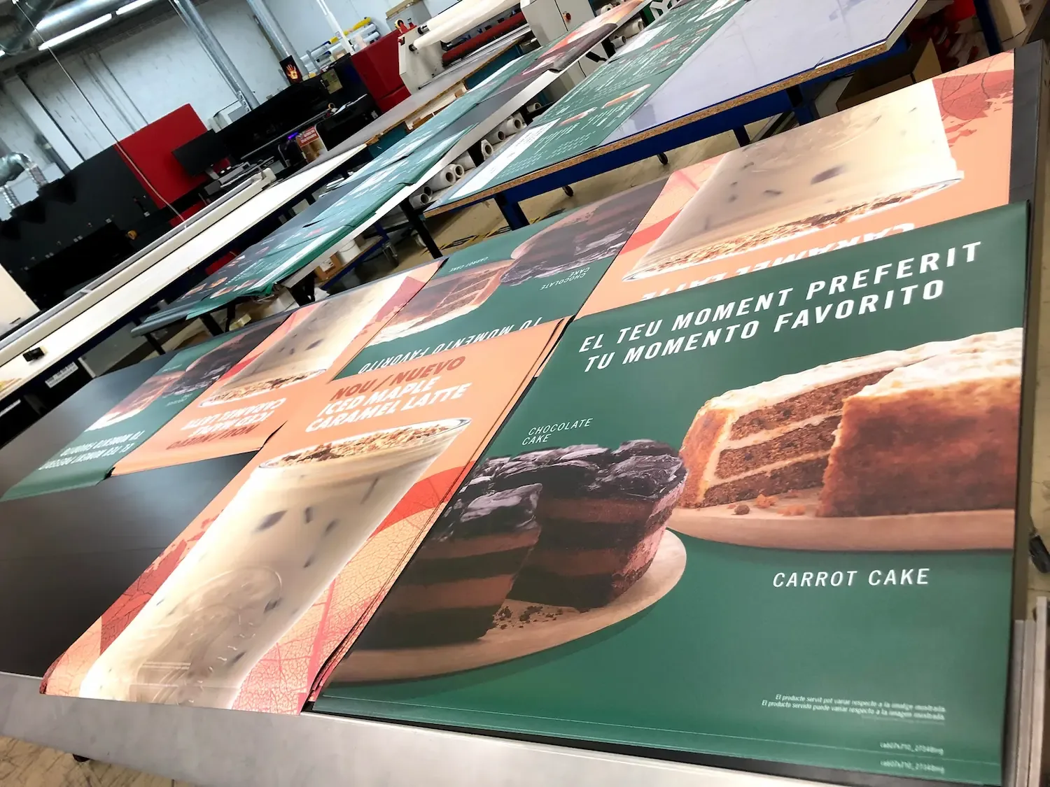 Posters van ijsdrankjes en taarten worden gedrukt op een werkbank in een drukkerij.