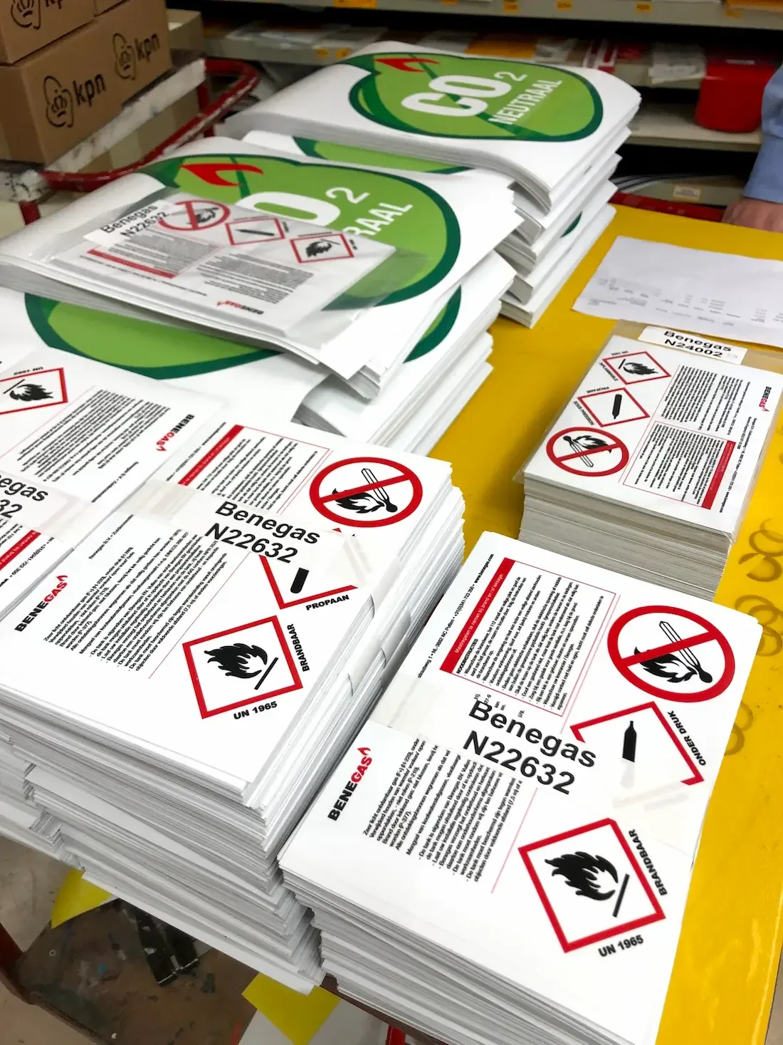 Stickers met veiligheidswaarschuwingen voor brandbare en CO2-neutrale producten liggen gestapeld op een tafel.
