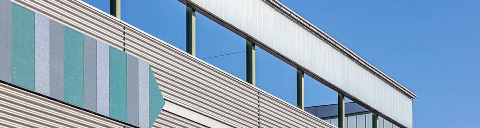 Buitenmuur met gekleurde pijlvormige panelen op een helderblauwe dag.