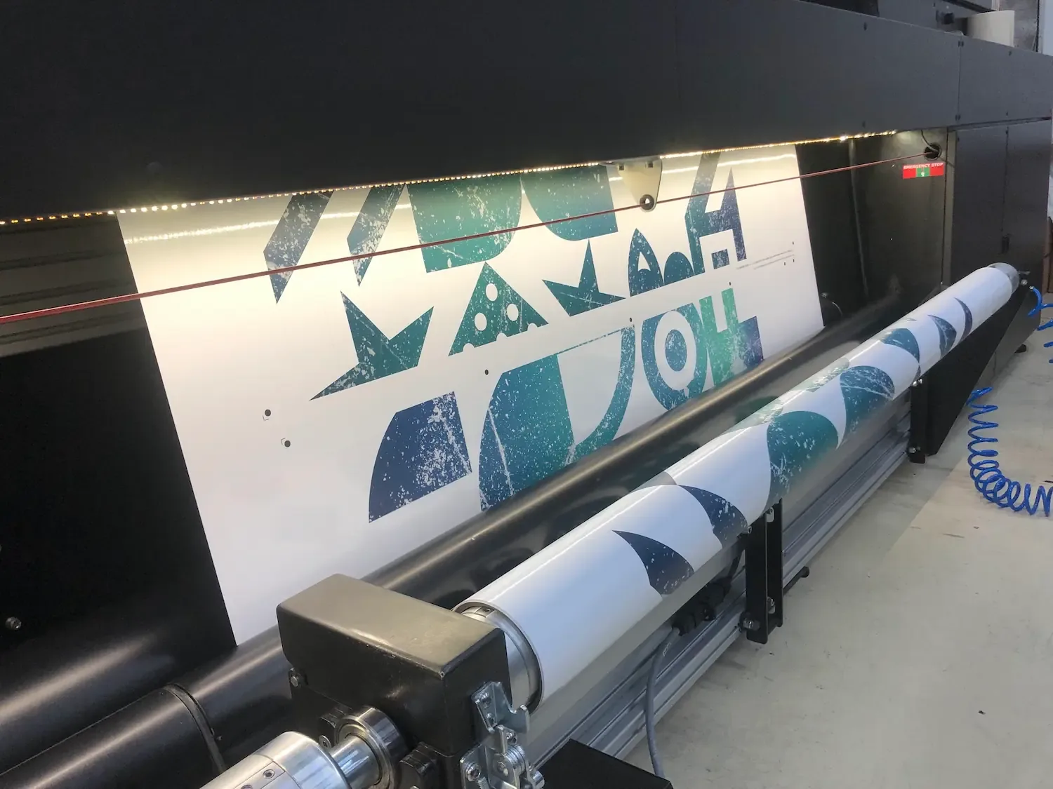 Een grote printer drukt een patroon af op een rol papier.