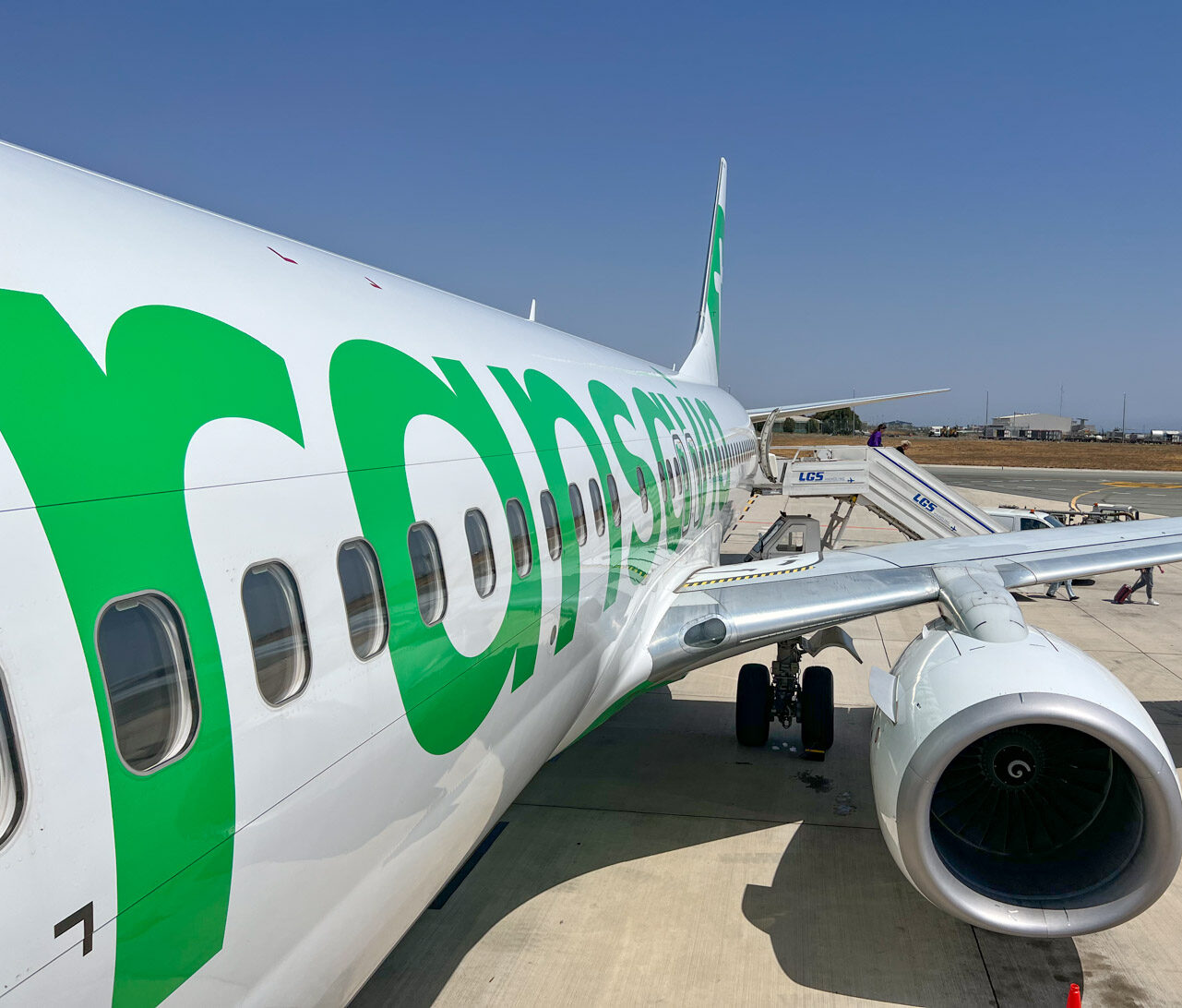 Een vliegtuig van Transavia staat geparkeerd op de luchthaven naast een passagierstrap.